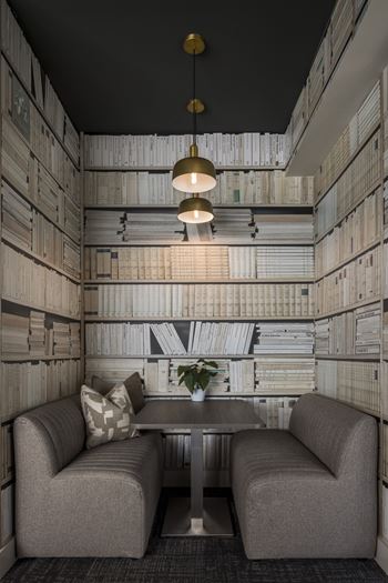 A room with a grey couch and a table with a vase of flowers on it.